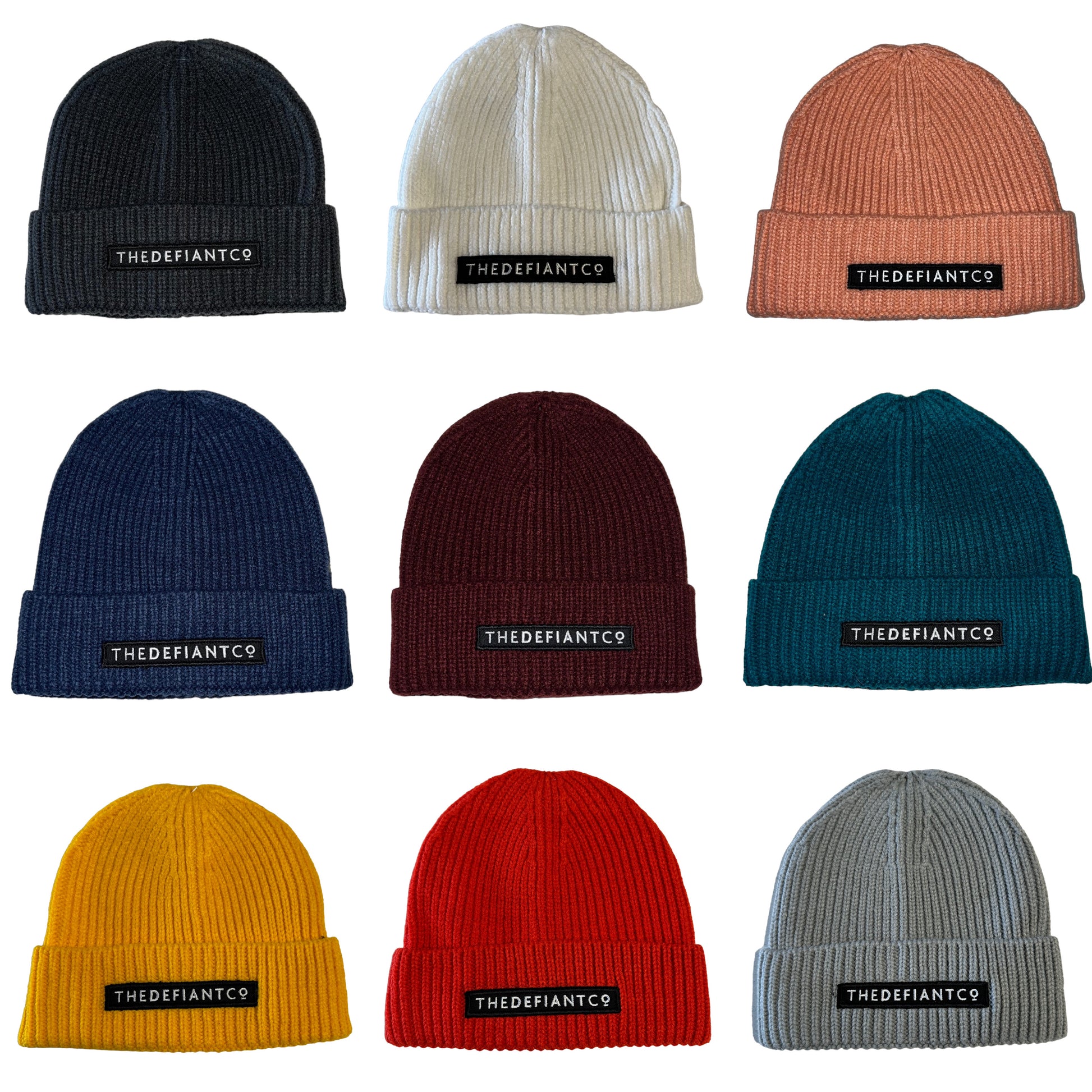 A collage showing a selection of beanie hats in a variety of colours. The hats have a ribbed finish with a roll cuff.  The cuff has The Defiant Co logo embroidered on the centre of the front in white on a black background.