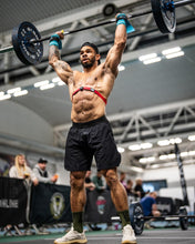 Load image into Gallery viewer, A guys wearing The Defiant Co Performance Shorts during a CrossFit workout demonstrating their ability to stand up to the most rigorous of workouts.  The guy is shredded and is performing shoulder to overhead with a barbell.  He is wearing the charcoal grey iteration of the best selling shorts.