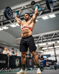 A guys wearing The Defiant Co Performance Shorts during a CrossFit workout demonstrating their ability to stand up to the most rigorous of workouts.  The guy is shredded and is performing shoulder to overhead with a barbell.  He is wearing the charcoal grey iteration of the best selling shorts.