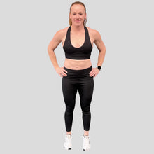 Load image into Gallery viewer, A photo showing the front of the amazing The Defiant Co Infinity Sports Bra.  The bra has a unique crossed back with The Defiant Co logo across both straps giving it a really standout look. The front is plain and simple giving it a really classy look. The colour is black.