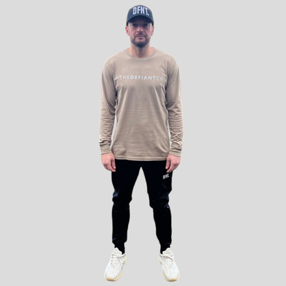 A photo showing ‘The Defiant Co’ long sleeved unisex t-shirt. The shirt has the famous ‘The Defiant Co’ logo across the front of the chest.  The shirt has a round neck and is slightly oversized. The shirt colour is sand.