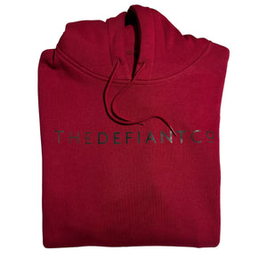 A photo of a standard fit, unisex The Defiant Co Hoodie.  The hoodie has draw strings and a pouch pocket on the front as per all standard designs.  The hoodie has the famous The Defiant Co logo across the front of the chest and is plain on the back.  The colour is burgundy.