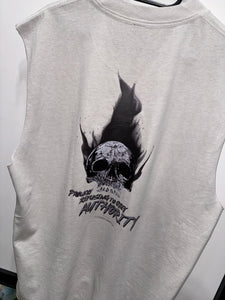 A photo showing the back of a unisex sleeveless t-shirt.  The shirt has a big bold print on the back of a skull in flames. Underneath the skull is the defiant tag line 'Proudly Refusing To Obey Authority' with the The Defiant Co logo under that. The sleeveless is faded bone in colour.