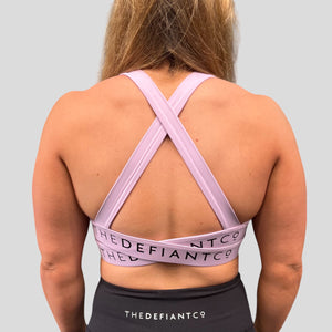 A photo showing the back of the amazing The Defiant Co Infinity Sports Bra.  The bra has a unique crossed back with The Defiant Co logo across both straps giving it a really standout look. The colour is lilac.