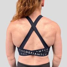 Load image into Gallery viewer, A photo showing the back of the amazing The Defiant Co Infinity Sports Bra.  The bra has a unique crossed back with The Defiant Co logo across both straps giving it a really standout look. The colour is navy blue.
