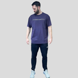 A photo showing a guy wearing an oversized The Defiant Co T-Shirt.  The shirt has the famous ‘The Defiant Co’ logo across the front of the chest.  The shirt has a round neck and is oversized.  The colour is Deep Purple.
