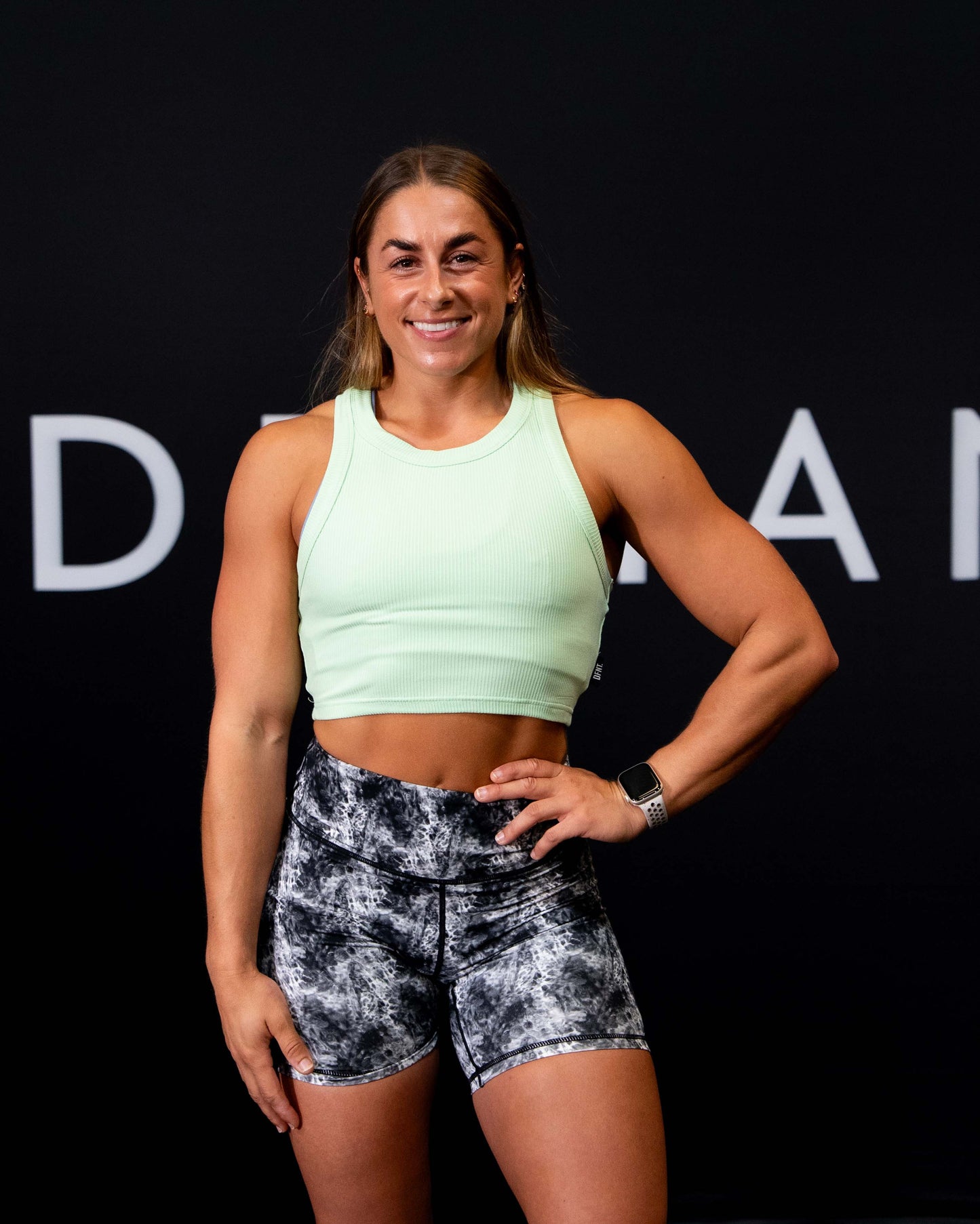 A girl against a black The Defiant Co backdrop wearing the DFNT. Ribbed Cropped Tank.  The tank is breathable with a stretchy fabric so is perfect for working out in.  It has a subtle DFNT. logo on a tag.  The colour is lime.