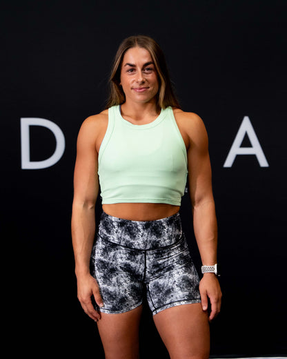 A girl against a black The Defiant Co backdrop wearing the Eternal 6 inch booty shorts.  The high waist and breathable material makes them perfect for any workout.  The colour is electric black and white.