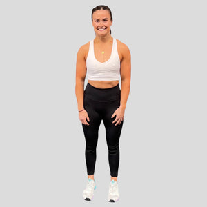 A photo showing the front of the amazing The Defiant Co Infinity Sports Bra.  The bra has a unique crossed back with The Defiant Co logo across both straps giving it a really standout look. The front is plain and simple giving it a really classy look. The colour is white.
