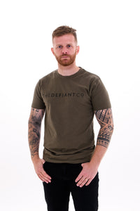 A guy with visible tattoos wearing The Defiant Co short sleeved t-shirt.  The t-shirt is 100% cotton and is extremely high quality making it a staple for the gym and beyond.  The famous The Defiant Co logo is embossed across the centre of the chest and the colour of the tee is olive green.
