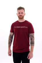 Load image into Gallery viewer, A guy with visible tattoos wearing The Defiant Co short sleeved t-shirt.  The t-shirt is 100% cotton and is extremely high quality making it a staple for the gym and beyond.  The famous The Defiant Co logo is embossed across the centre of the chest and the colour of the tee is burgundy.