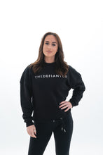 Load image into Gallery viewer, A photo showing The Defiant Co women&#39;s oversized crewneck. The crewneck has a roundneck and draw string around the bottom. The crews have the famous The Defiant Co logo across the front of the chest and are plain on the back. The colour is black.