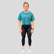 Load image into Gallery viewer, A photo showing a female fit, slightly oversized, cropped acid wash t-shirt. The shirt has the famous ‘The Defiant Co’ logo across the front of the chest.  The acid Wash effect of the shirt means no two are alike and provides the perfect blend of fashion and defiance. The shirt is teal in colour with a slightly black wash.