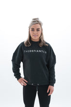 Load image into Gallery viewer, A photo showing The Defiant Co women&#39;s oversized crewneck. The crewneck has a roundneck and draw string around the bottom. The crews have the famous The Defiant Co logo across the front of the chest and are plain on the back. The colour is charcoal grey.