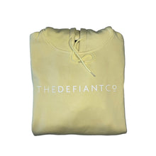 Load image into Gallery viewer, A photo of a standard fit, unisex The Defiant Co Hoodie.  The hoodie has draw strings and a pouch pocket on the front as per all standard designs.  The hoodie has the famous The Defiant Co logo across the front of the chest and is plain on the back.  The colour is butter.