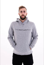 Load image into Gallery viewer, A guy wearing a standard fit, unisex The Defiant Co Hoodie.  The hoodie has draw strings and a pouch pocket on the front as per all standard designs.  The hoodie has the famous The Defiant Co logo across the front of the chest and is plain on the back.  The colour is heather grey.